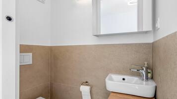 A bathroom with a white sink, a mirror, and a toilet.