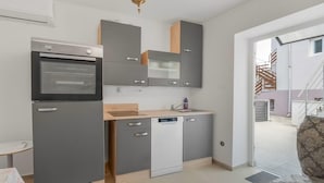 Cocina compacta con horno integrado, lavavajillas y encimera de madera.