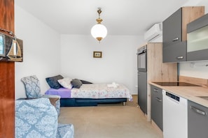 A compact room with a bed, a small seating area, a kitchenette, and a ceiling light fixture. - Peaceful Holiday Home Near Baška (Draga Bašćanska)