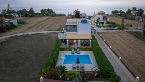 Una villa moderna con piscina, un patio coperto e vista sul mare.