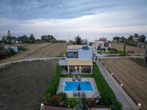 Eine moderne Villa mit Swimmingpool, überdachter Terrasse und Meerblick.