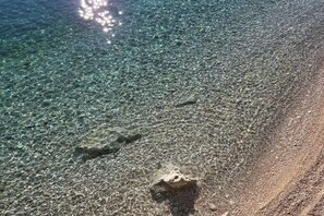 A clear beach with visible pebbles and a rock formation. - Seaside apartment in Lokva Rogoznica (Lokva Rogoznica)
