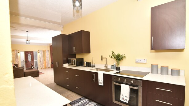 A modern kitchen with dark cabinetry, a stainless steel oven, and a white countertop. - Spacious 3-bedroom apartment in adorable Gros Islet with AC near popular spots (Gros Islet)