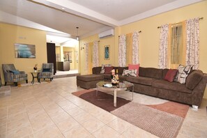 Ein Wohnzimmer mit einer Couch, Sesseln, einem Couchtisch und einem Essbereich mit Stühlen und einem Tisch.