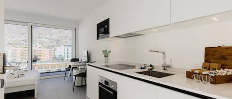A modern kitchen with a large window, a dining area, and a bed.