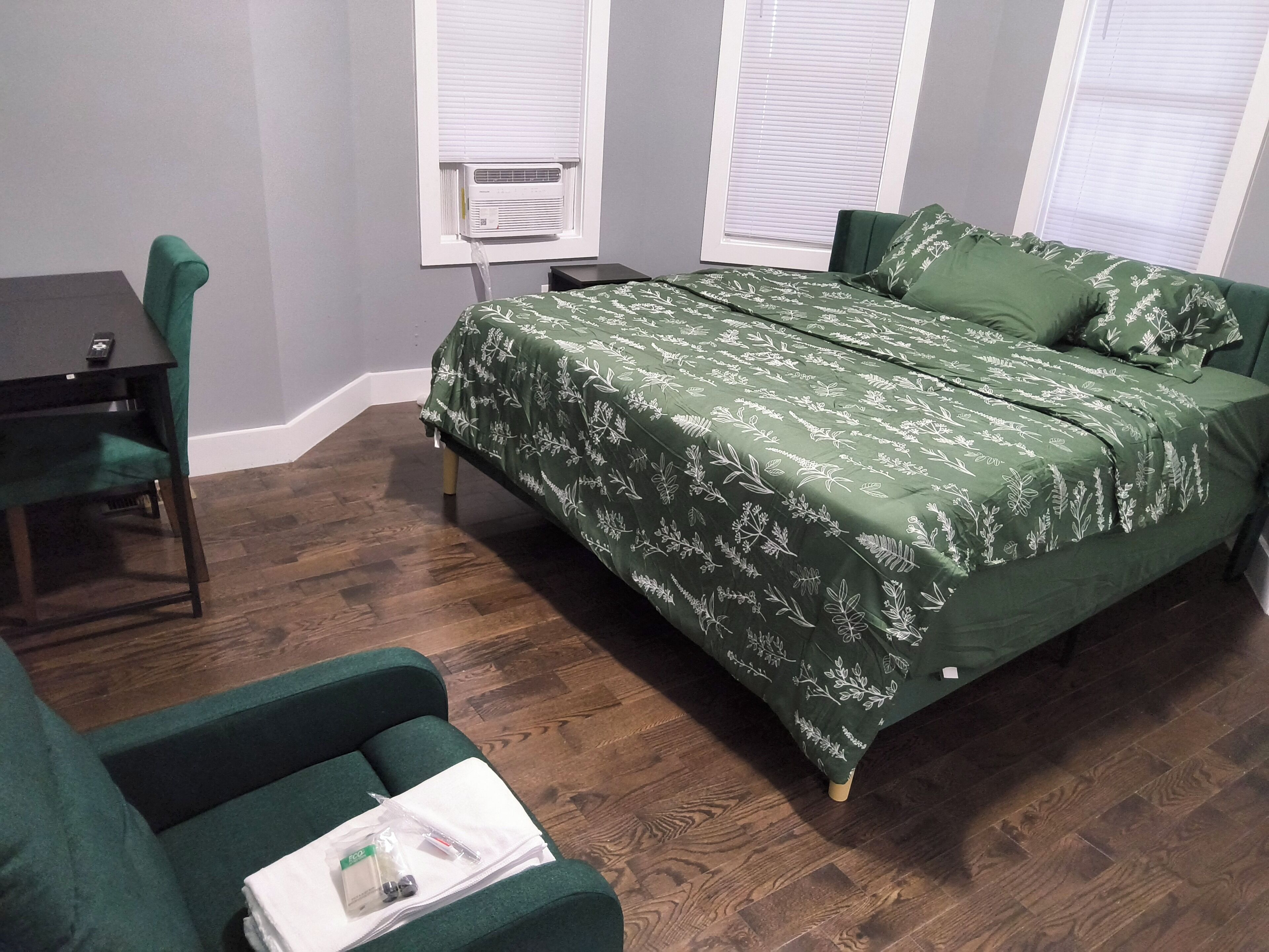 A bedroom with a green bed, a desk, and a chair.
