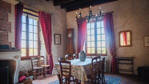 Ein Esszimmer mit einem Tisch, der für sechs Personen gedeckt ist, umgeben von Stühlen, einer Kristallleuchtre und einem Kamin.