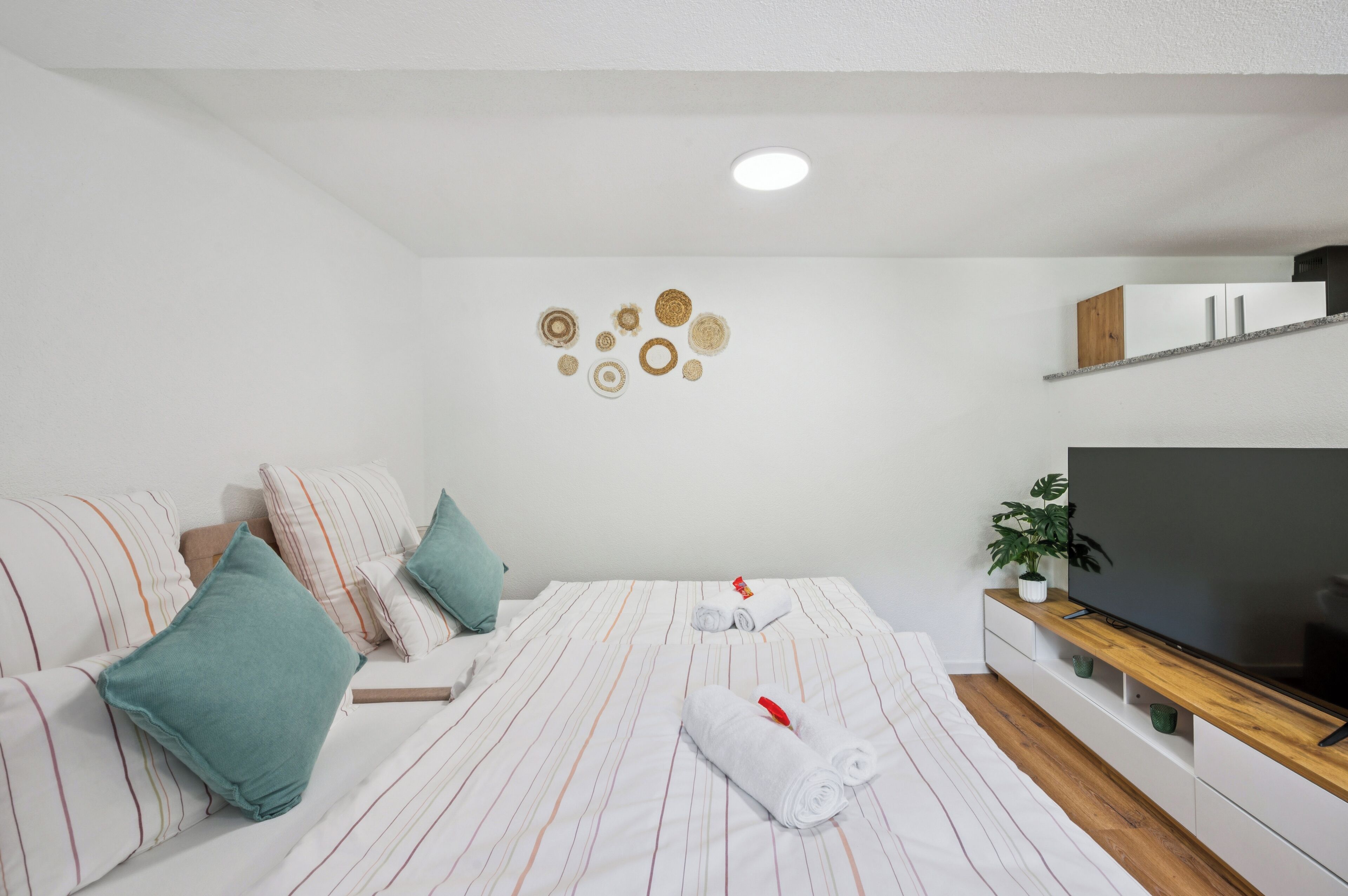 Une chambre d’hôtel moderne équipée d’un lit, d’oreillers, d’une télévision et d’un élément décoratif mural.
