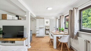 Une chambre moderne équipée d’une télévision, d’une table à manger, de chaises et d’une fenêtre avec des rideaux.