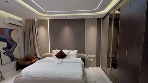 A modern bedroom with a large bed, a wardrobe, and a unique ceiling design. - 501 Aparthotel (Akure)