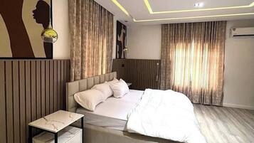 A modern bedroom with a bed, bedside tables, and a wall with a silhouette artwork.