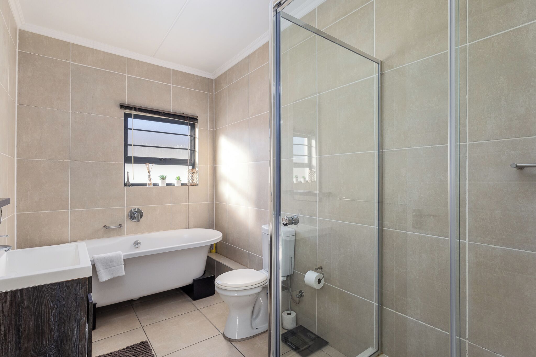 A bathroom with a bathtub, toilet, and glass shower enclosure.