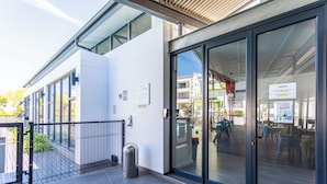 Un edificio moderno con ampie porte e finestre in vetro, una recinzione in metallo e un cestino.