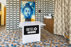 A hotel reception area with a Buddha painting, a sign indicating OYO-Serviced, and a patterned floor. - Classic Sri Jogulamba Residency (Balanagar)