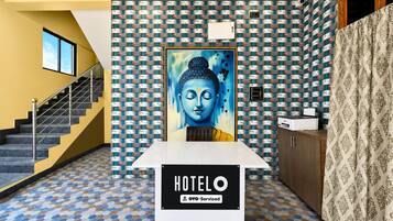 A hotel reception area with a Buddha statue, a staircase, and a patterned floor.