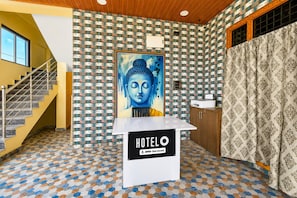 A hotel reception area with a Buddha painting, a staircase, and a tiled floor. - Classic Sri Jogulamba Residency (Balanagar)