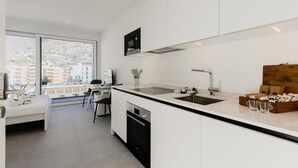 A modern kitchen with a large window, a dining area, and a bed. - {Suite 511} Gym, Business Room, Modern, Relax (Lugano)