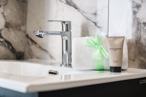 Ein Badezimmer mit Marmorwaschbecken, einem Handtuch und einer Balsamo Conditioner-Flasche.