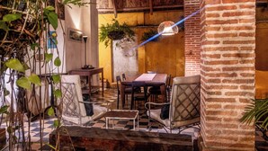 A rustic interior with a checkered floor, wooden furniture, and a brick wall. - CASA DE COLUMNAS (Cartagena)