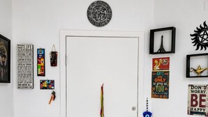 A white door with a circular emblem above it, a black door handle, and a blue eye-shaped lock. - Apto Rodoviária e Mercado Municipal (Curitiba)