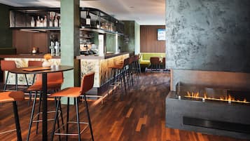 Eine Bar mit einer langen Theke, Hockern und einem Kamin.