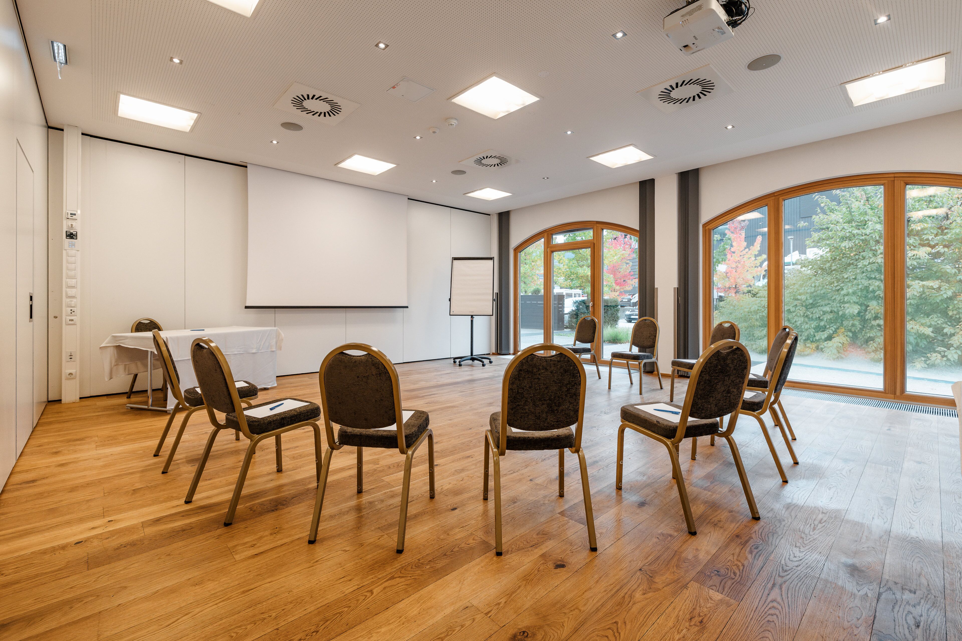 A conference room with a whiteboard, projector, and multiple chairs arranged for a meeting.