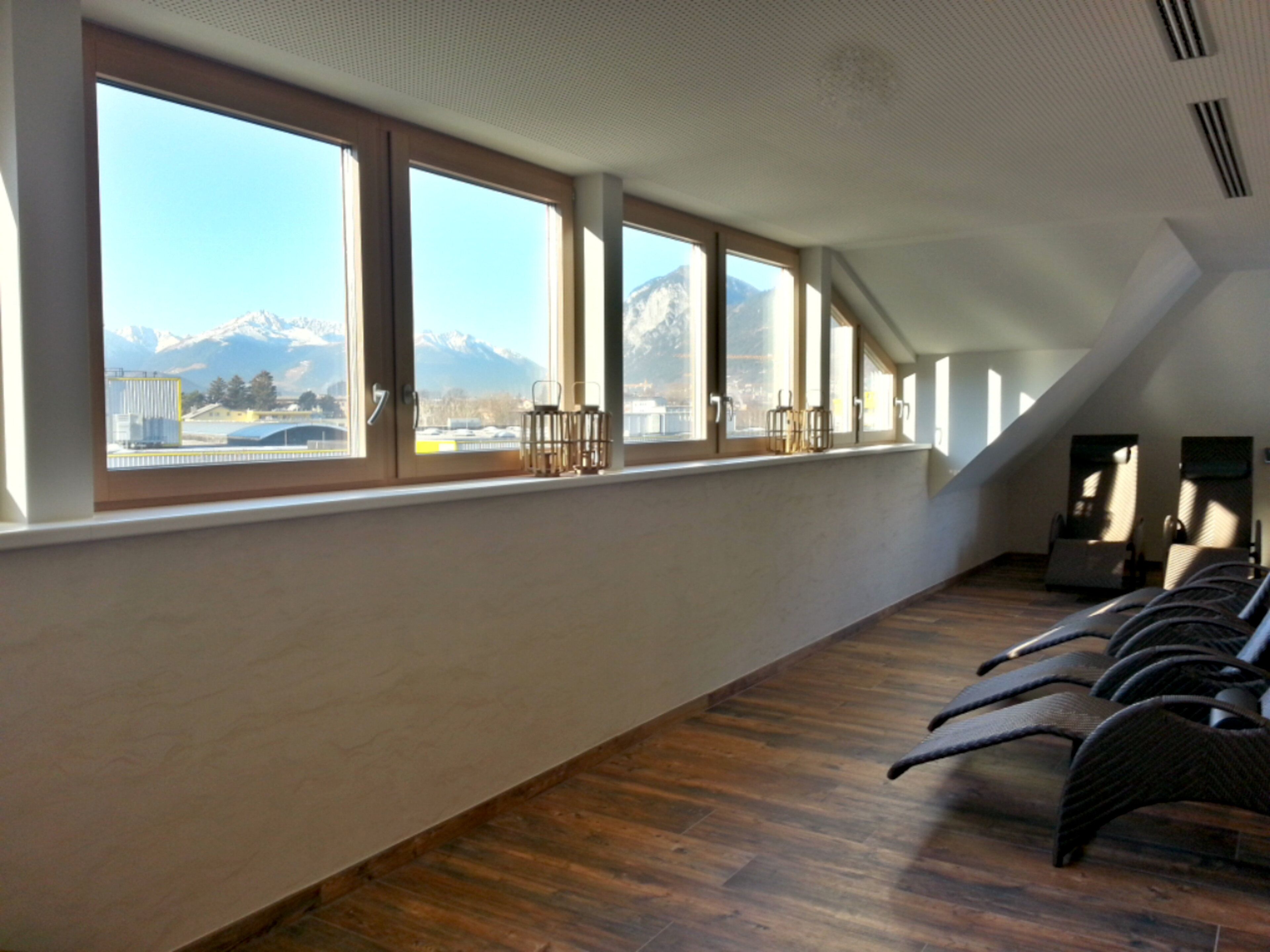 Ein Zimmer mit großen Fenstern, Holzboden und Bergblick.