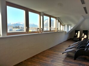 A room with large windows, wooden flooring, and a view of mountains.