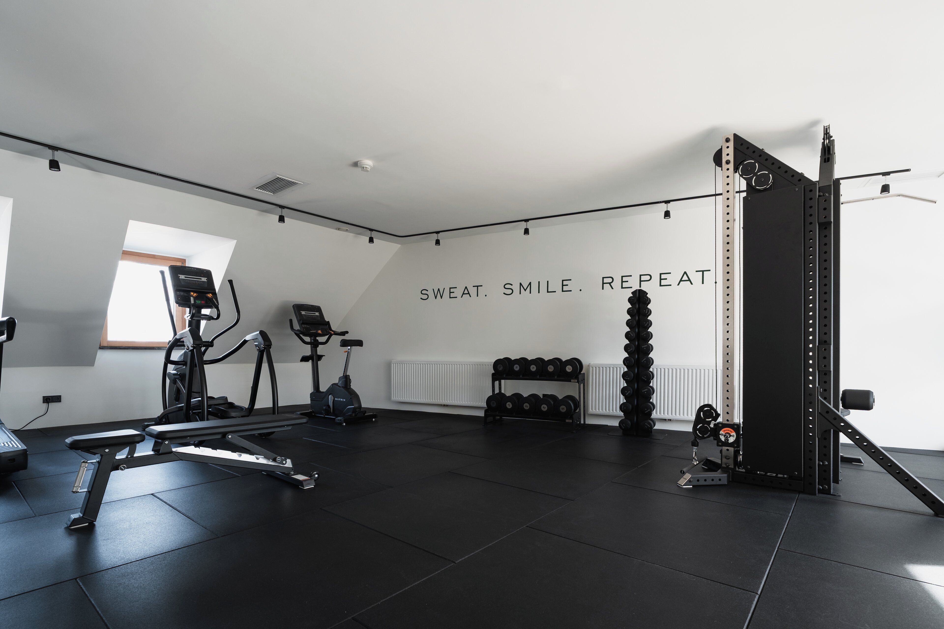 Ein Fitnessstudio mit Trainingsgeräten, einer Wand mit motivierenden Texten und einem Fenster.