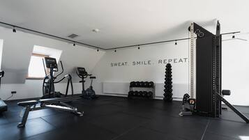 Ein Fitnessstudio mit Trainingsgeräten, einer Wand mit motivierenden Texten und einem Fenster.