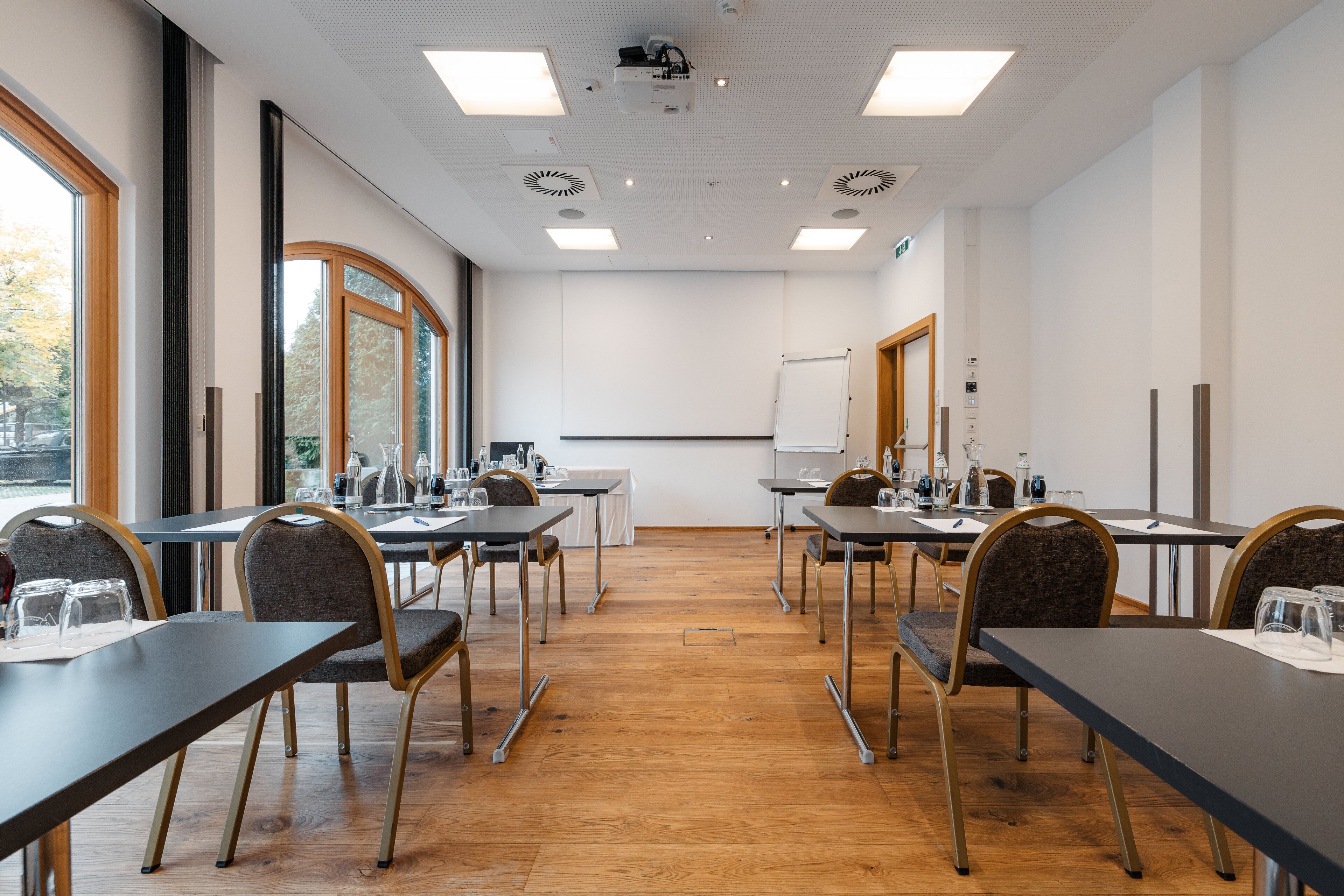 Ein Konferenzraum mit Tischen, Stühlen und einer Projektionsleinwand.