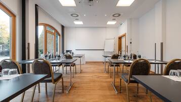 Ein Konferenzraum mit Tischen, Stühlen und einer Projektionsleinwand.