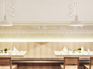 A restaurant with a clean, modern design featuring wooden furniture and white table settings. - Holiday Inn Innsbruck by IHG (Innsbruck)