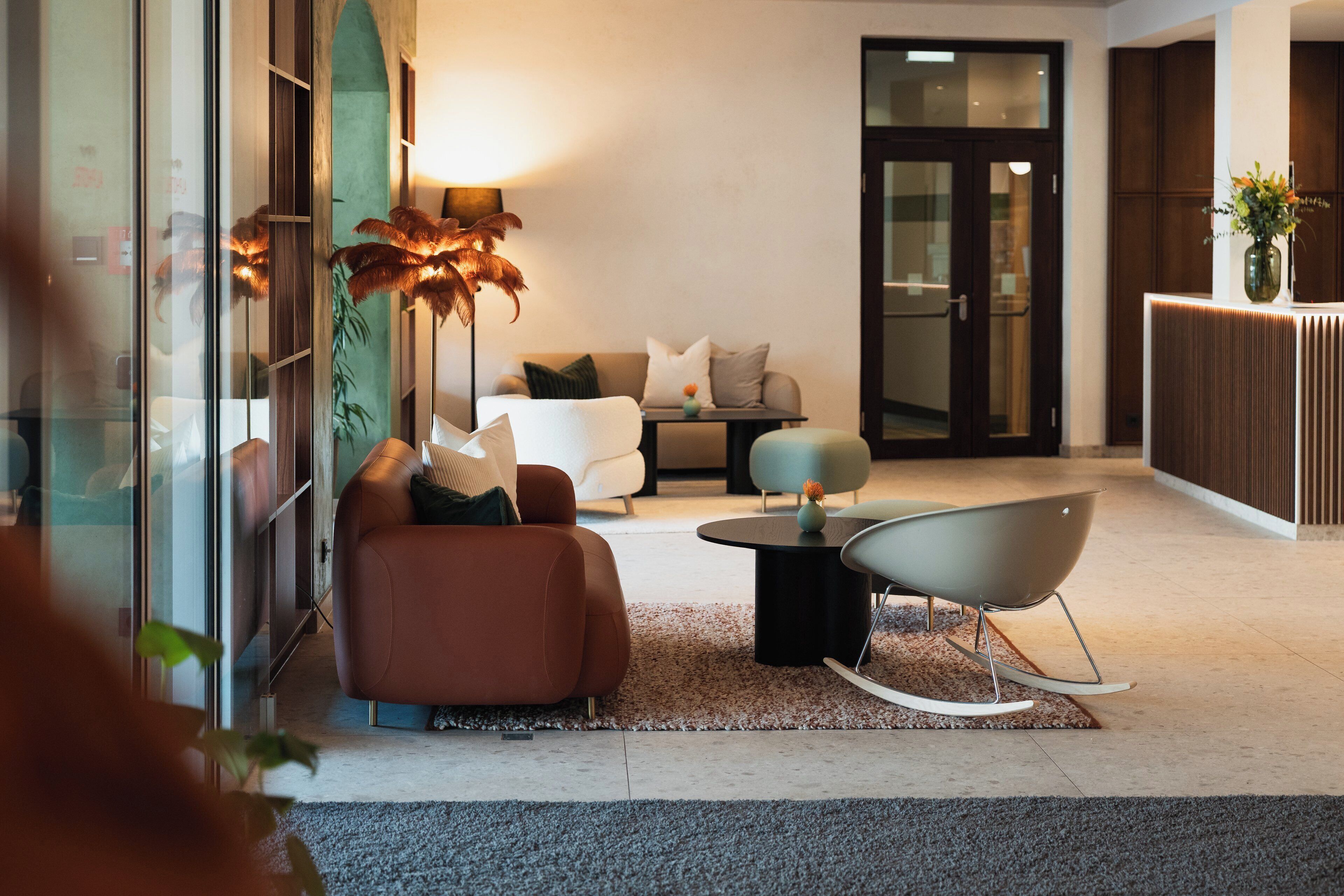 A modern lobby with a sofa, chairs, a coffee table, and a reception desk.