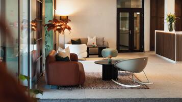 A modern lobby with a sofa, chairs, a coffee table, and a reception desk.