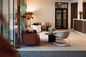 Um lobby moderno com sofá, cadeiras, mesa de centro e balcão de recepção.