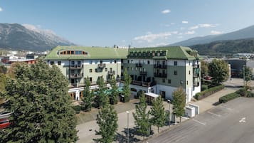 A multi-story hotel with a green roof, surrounded by trees and a parking lot.