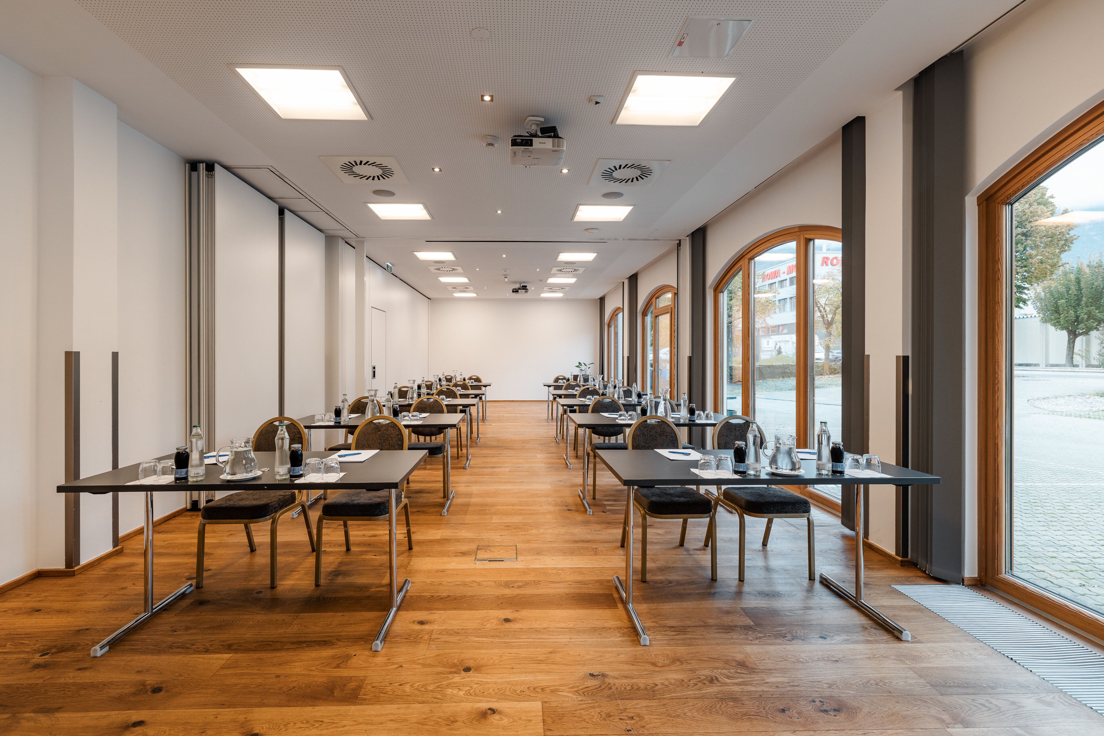 A conference room with long tables, chairs, and a large window.
