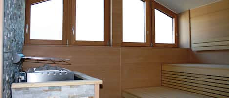 Cocina compacta con protector de piedra, estufa integrada y banco de madera.