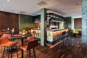 Un espacio moderno de bar con barra, asientos y una pared decorativa.