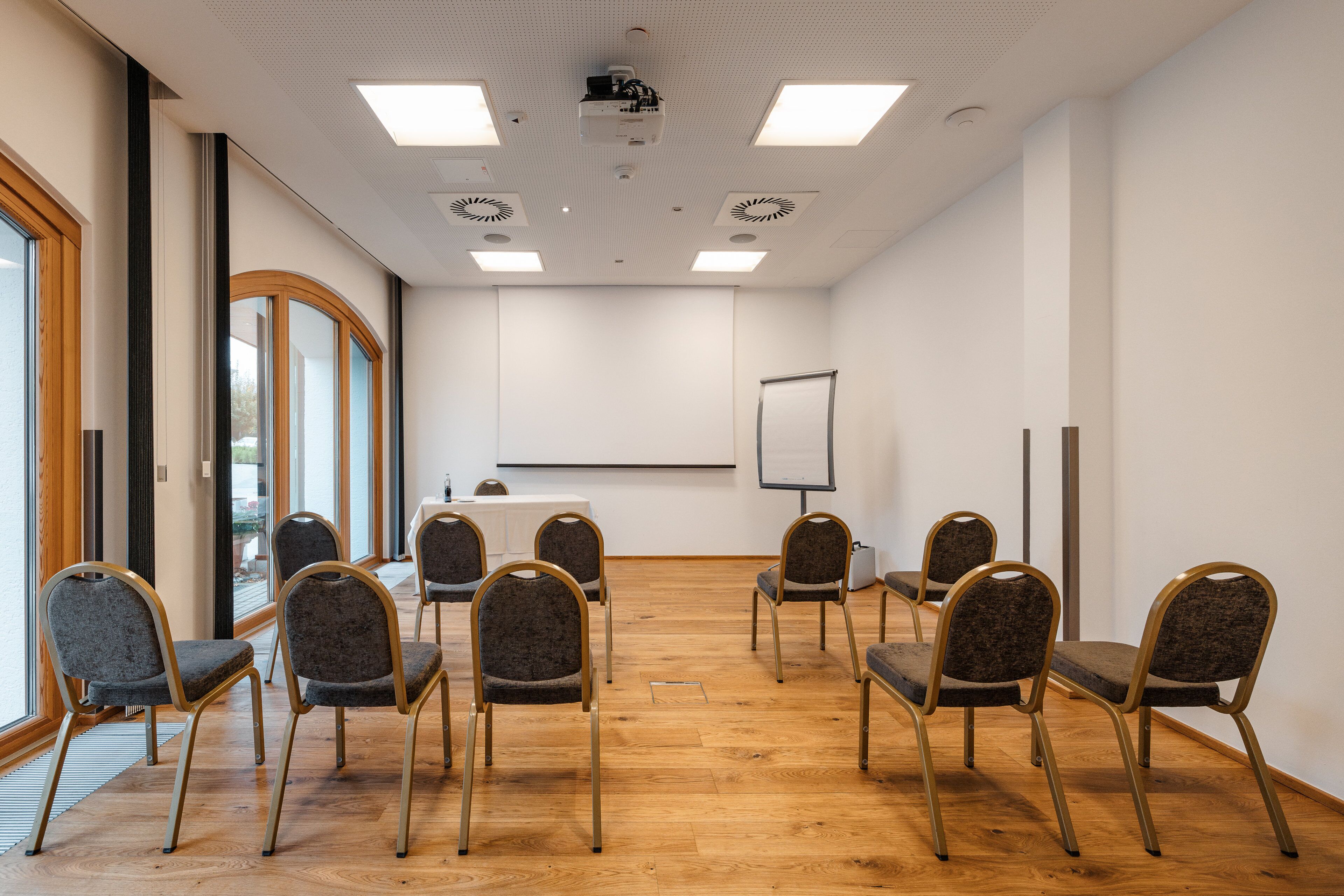 Ein Konferenzraum mit einer Whiteboard, Projektor und sechs Stühlen, die um einen Tisch angeordnet sind.
