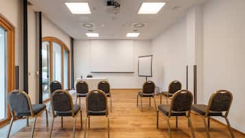 Ein Konferenzraum mit einer Whiteboard, Projektor und sechs Stühlen, die um einen Tisch angeordnet sind.
