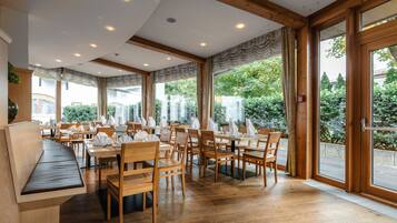 Un restaurante con muebles de madera, ventanas amplias e iluminación empotrada en el techo.