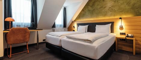 Habitación de hotel con cama doble, escritorio, silla, lámpara y teléfono.