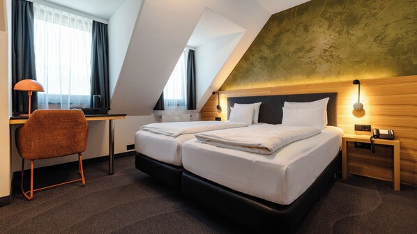 A hotel room with a double bed, a desk, a chair, a lamp, and a telephone.