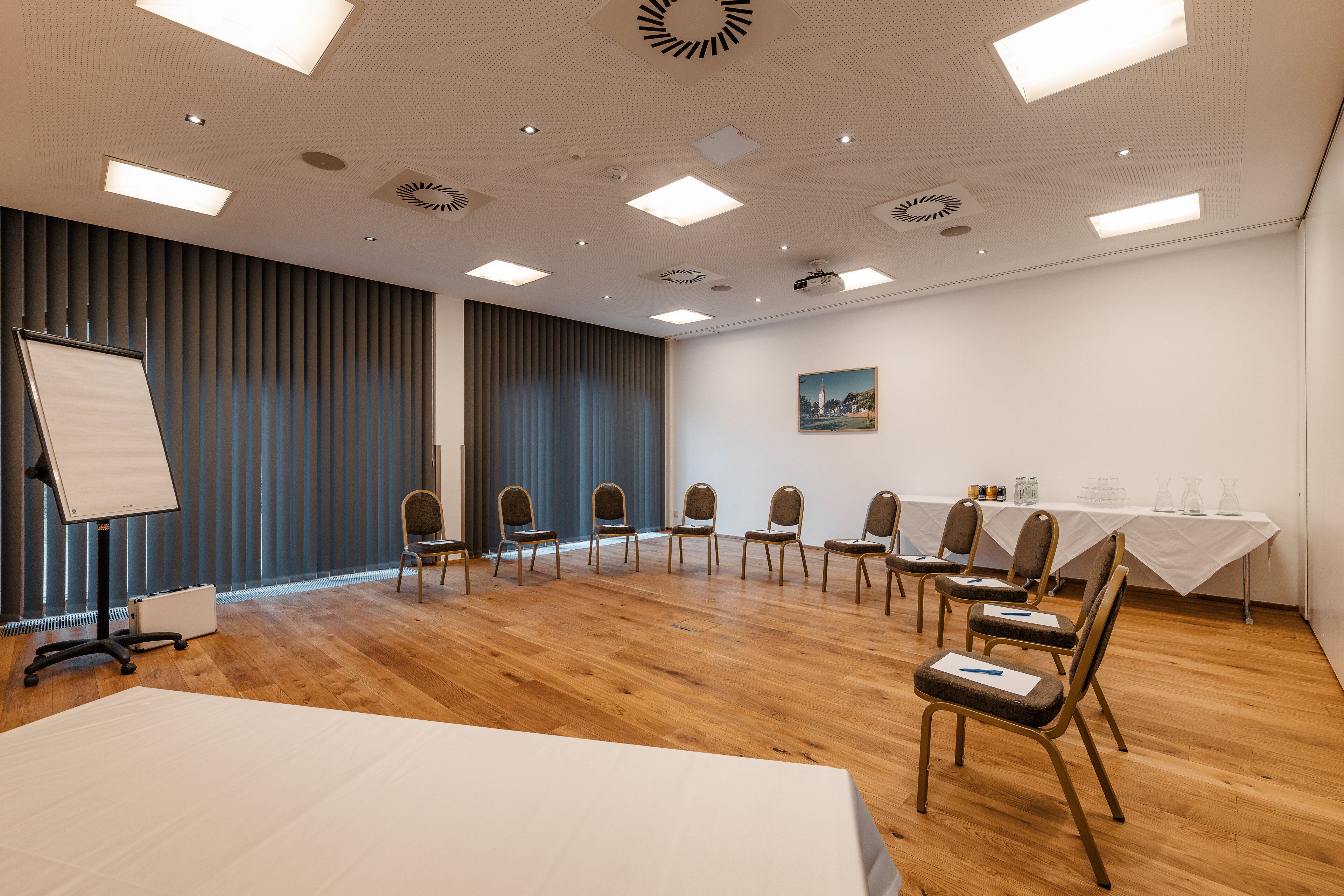 Una sala de conferencias con una pizarra, un proyector y una mesa con sillas.
