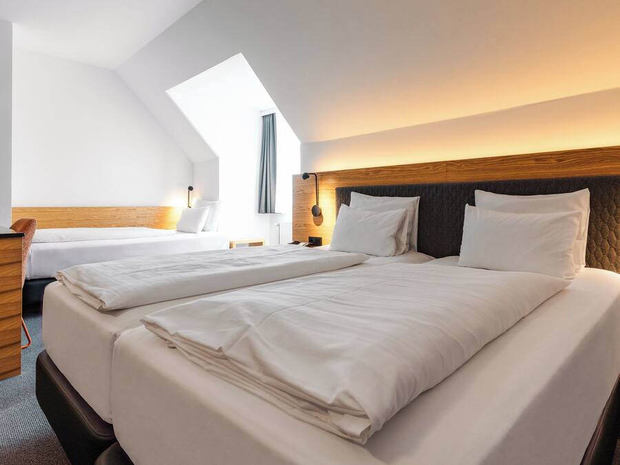 Une chambre d’hôtel avec deux lits, un bureau, une lampe et une vue sur le ciel.