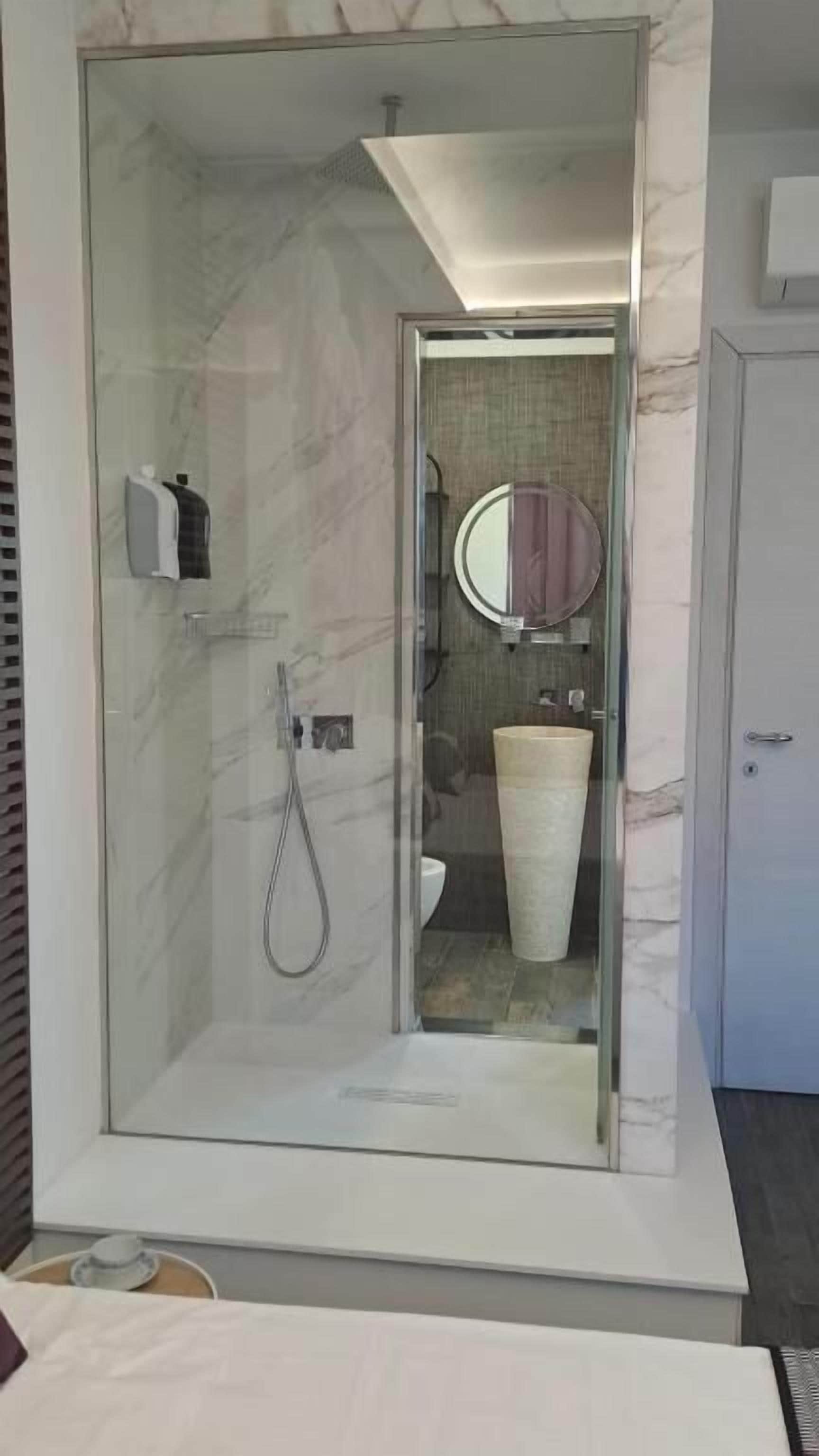 Habitación Deluxe doble, balcón, vistas parciales al mar | Baño | Ducha, artículos de higiene personal gratuitos y secador de pelo