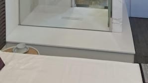 Un baño moderno con cabina de ducha de vidrio, un espejo grande y un inodoro.