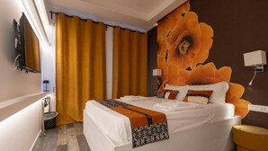 Habitación de hotel moderna con una cama grande, un televisor montado en la pared, una mesita de noche y un mural floral de gran tamaño en la pared.